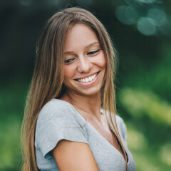 portrait of young smiling attractive caucasian woman in jeans jacket in the park at summer