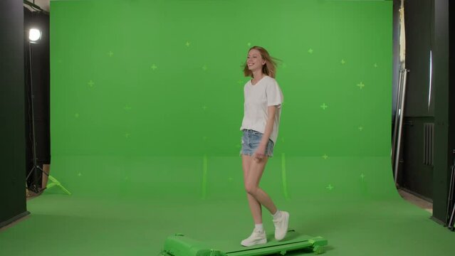 Woman in white t-shirt, jeans shorts and sneakers walking on a Green Screen, Chroma Key. 4k UHD front side view footage video