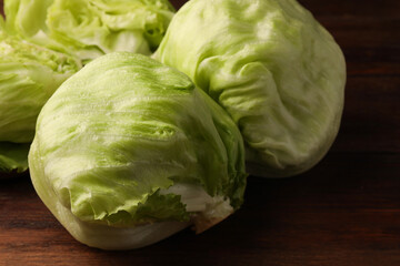 Fresh green whole and cut iceberg lettuce heads on wooden table, closeup