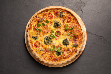 Delicious homemade vegetable quiche on dark table, top view
