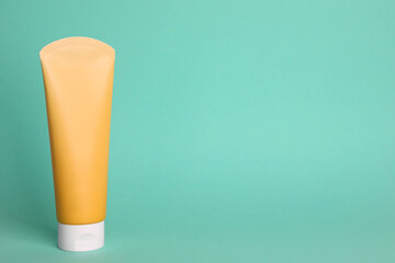 Tube of face cleansing product on turquoise background. Space for text