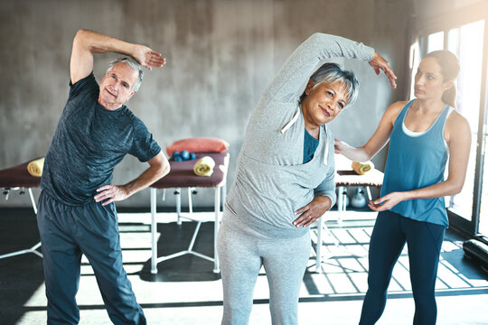 Stretching, help and old couple with personal trainer for fitness, wellness and physiotherapy. Health, workout or retirement with senior patient and physiotherapist in gym for warm up training