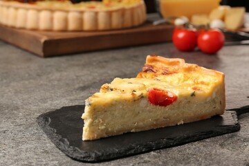 Piece of delicious homemade cheese quiche on gray table