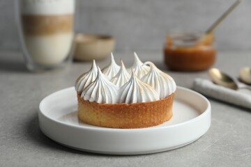 Tartlet with meringue on grey table, closeup. Delicious dessert