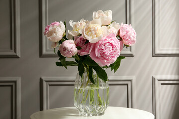 Bouquet of beautiful peonies in glass vase on white table