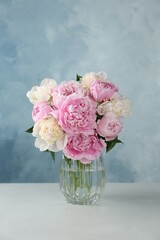Bouquet of beautiful peonies in glass vase on white table