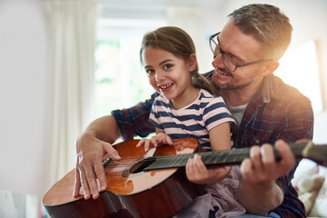 Father, guitar and teaching a girl in portrait with happiness at home for fun or love or bonding. Music, acoustic and instrument with parent and daughter for learning or care with music together. - Powered by Adobe
