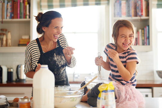 Mother, play or child baking in kitchen as a happy family with an excited girl learning cookies recipe. Cake, daughter laughing or funny mom helping or teaching kid to bake with smile for development