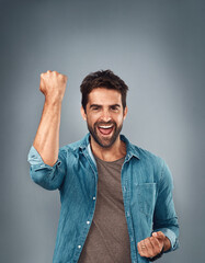 Happy man, fist and celebration for winning, success or victory against a grey studio background....