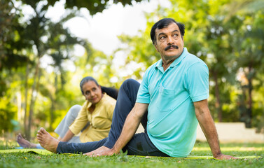 Indian elderly senior people at park doing stretching exercise or yoga asana - concept of active...