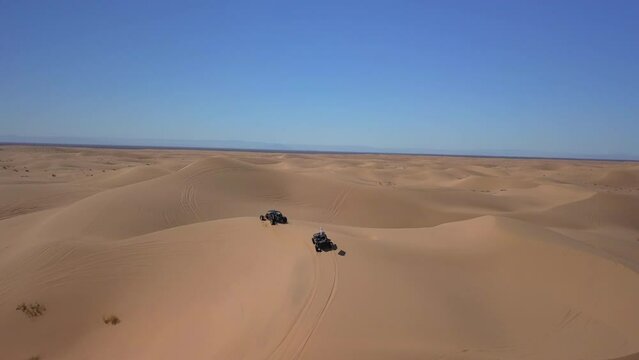 Aerial Panning Shot Of Dunes Buggies On Sand Against Blue Sky, Drone Flying Over Desert Landscape - Glamis, California