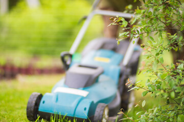 Lawn mover on green grass in modern garden or backyard. Machine for cutting lawns. Gardening care tools and equipment