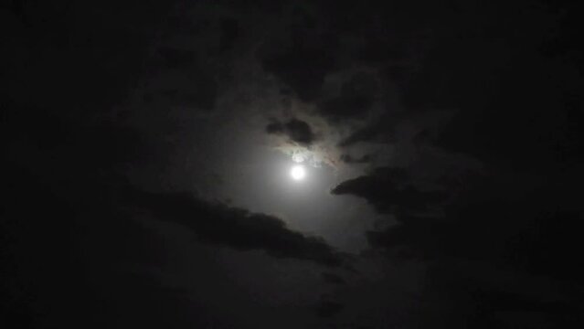 Black dark night sky with clouds and a round glowing moon