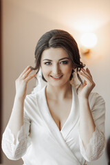 Portrait of a brunette bride touching her face. Gorgeous make-up and hair. Voluminous veil. Wedding photo. Beautiful bride