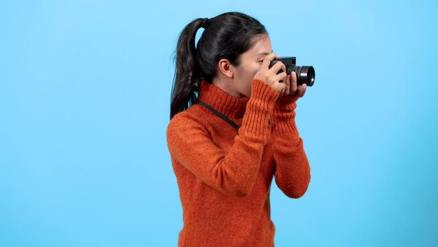 Portrait woman tourists lifestyle traveling concept, cute Asia young photographer hold camera take photos in studio background, blogger girls using camera take photos to create traveling content