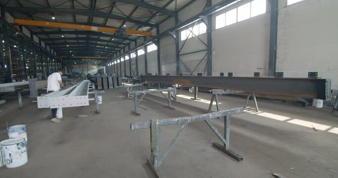 Workers during the process of fabrication of metal elements for hall construction in the workshop, wide shot, pan left.