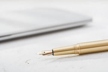 Golden fountain pen with blurred notebook on vintage desk surface