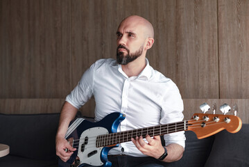 Handsome bald man with beard playing bass guitar. Professional musician