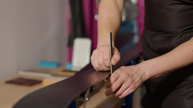 Man sharping ski edges with file tool at the workshop