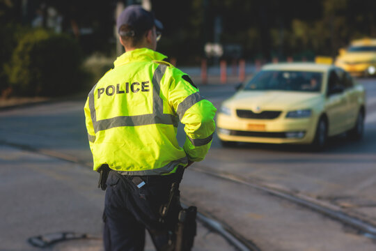 Inspector Of Traffic Police Highway Patrol Regulates The Movement Of Transport In The Center Of European City, In Green Yellow Vest Jacket With A Sign 