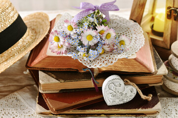 A bunch of daisy and forget-me-not flower lying on a stack of old books