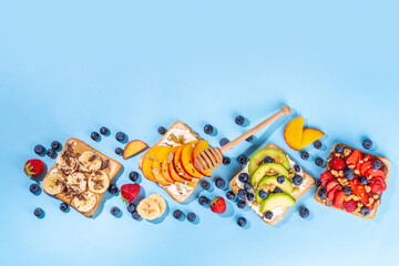 Fruit berry sandwiches. Various toasts with peanut butter, cream cheese, chocolate spread with summer berries and fruits - strawberry, banana, peach, apple, blueberry, Tasty morning lunch food