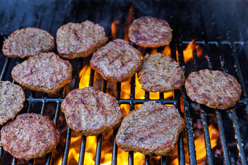 Cooked grilled beef meat barbecue burgers for hamburgers on bbq fire flame grill as part of cooking process