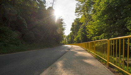 Zakręt na asfaltowej drodze , ze stalowymi żółtymi barierkami , biegnącej we wzgórzystym...