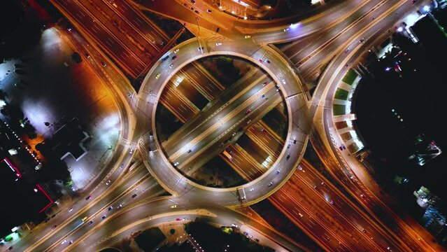 Aerial time lapse view of multilevel junctio highway interchange with car traffic and light trails during night time