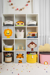 White shelving with colorful storage baskets and boxes with toys. Interior design. Organizing and...