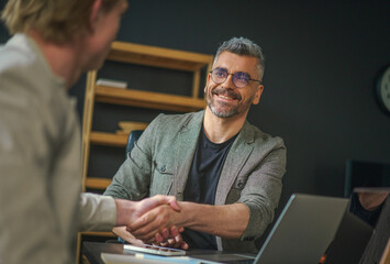 Two businessmen confidently greet each other with handshake, symbolizing successful deal and beginning of promising partnership. Their professional demeanor and mutual trust reflect essence business