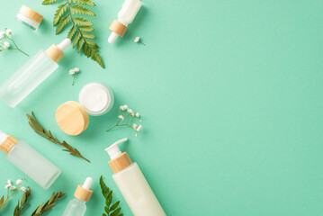 Organic cosmetics products concept. High angle view photo of cosmetic jars and bottles with bracken and eucalyptus leaves and gypsophila flowers on isolated turquoise background with copyspace