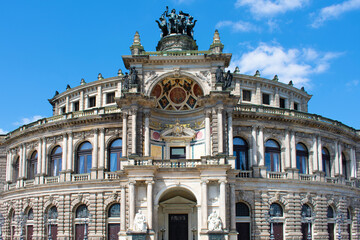 Obraz premium Facade of ancient architectural building with beige walls, statues, decorative elements, semicircular windows and arch. Historical architecture. Old town. Opera House. Dresden, Germany, May 2023 