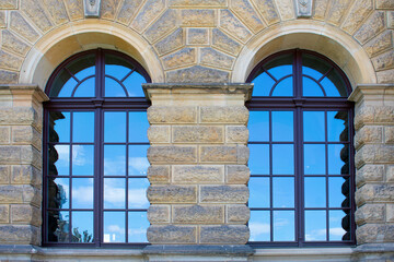 Facade of the historic building with blue semicircular windows and grey and beige brick wall. Ancient architecture. Sunny summer day. Dresden, Germany, May 2023