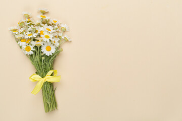 Small bouquet of chamomile flowers on color background, top view