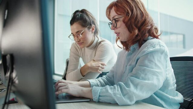 Web developers having a discussion and working on a computer program. Business women collaborating on a software engineering project in an office. Creative female professionals working in a tech.