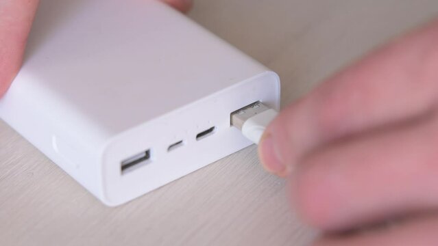 Close up of a male hands plugging in the usb cable into the power bank to recharge his phone