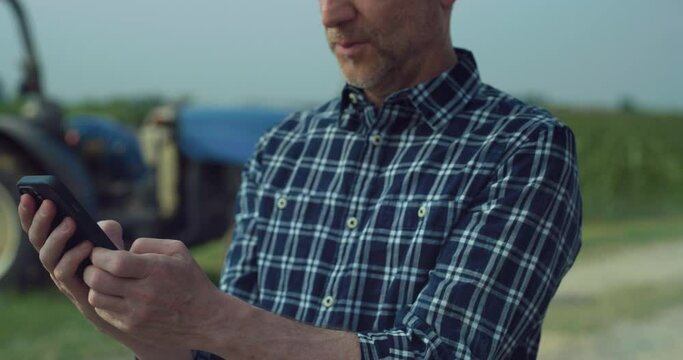 Close Up of a Middle Aged Man Using Smartphone to Stay Connected with Family and Friends During Work on a Corn Field. Professional Farmer Making Online Purchases for his Crops, Using Technology