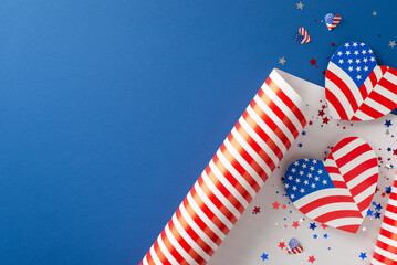 Get into spirit of Independence Day in USA. Top view of specially designed wrapping paper for gifts, showcasing hearts adorned with flag pattern. Confetti spread across blue backdrop, space for text