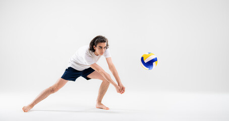 Fototapeta na wymiar A young volleyball player is training with a ball on a white background. Action, sport, health, team, fitness concept