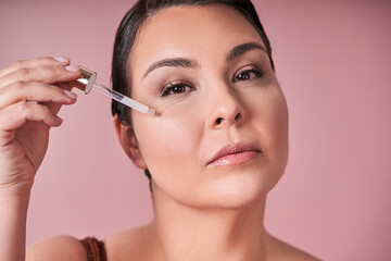 Fototapeta premium Body positive woman applying serum on face
