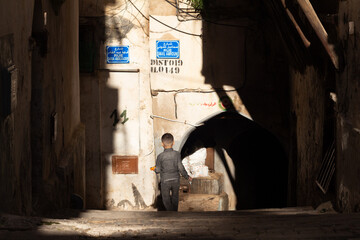 Street scene in the Casbah of Algiers (Alger), Algeria. Young boy walking. Stone stairs and ancient ottoman houses. Chiaroscuro atmosphere. - obrazy, fototapety, plakaty