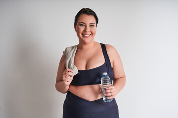 Portrait of happy plus size woman holding water bottle