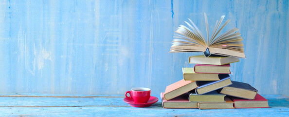 Open book, hardback books and cup of coffee on blue background.Literature, education,reading and...