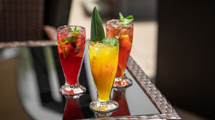 Three glasses of different fruit fresh lemonades on cafe table