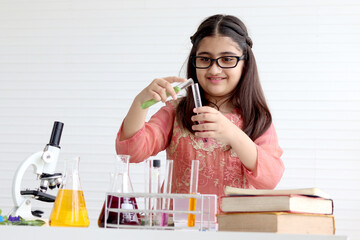 Cute Indian school girl in India traditional dress costume doing science experiments in laboratory,...