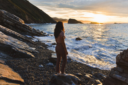 Anonymous woman admiring sea during sunset