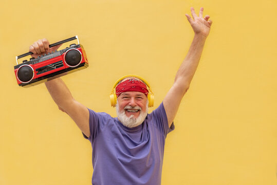 Excited man with cassette player and headphones raising hands