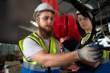 Both of engineers installing and testing a large robotic arm. before sending it to customers for use in the industry