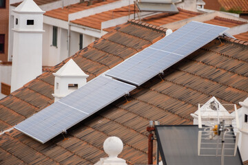 Group of solar panels on the roof of single-family houses. Solar panels. Clean energy. Ecology. Red roof tiles. Tenerife, Canary Islands, Spain